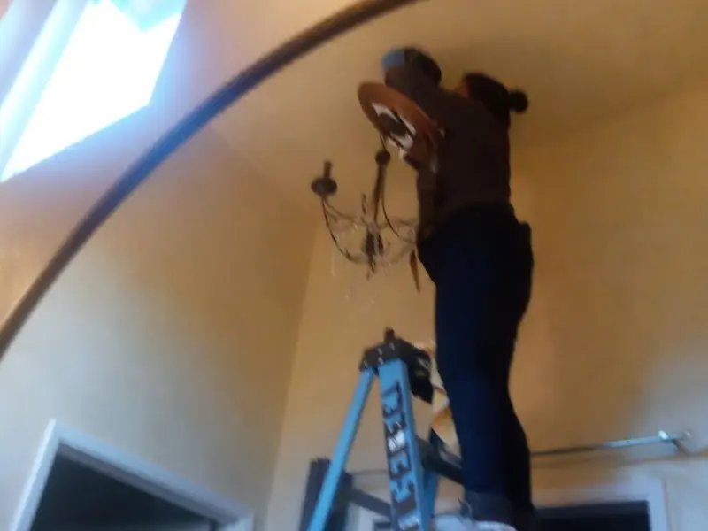 Electrician installing a chandelier in a Freeland residence